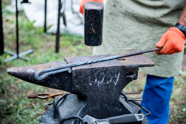 blacksmith works on an anvil Master forges product Tools and blacksmith anvil Blacksmith working outdoors