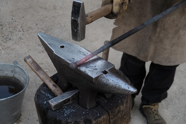 A blacksmith works the forge with a hammer on an anvil