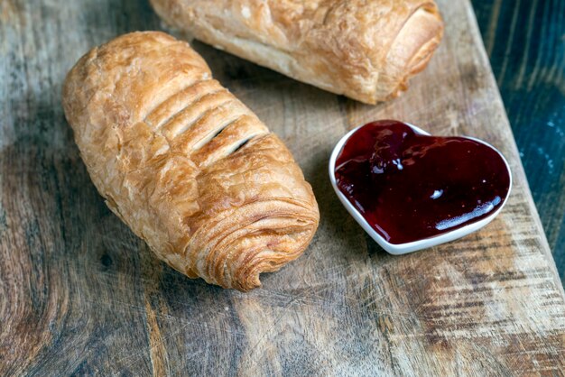 Bladerdeeg met rode aardbeienjam op een houten tafel