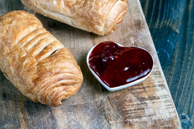 Bladerdeeg met rode aardbeienjam op een houten tafel