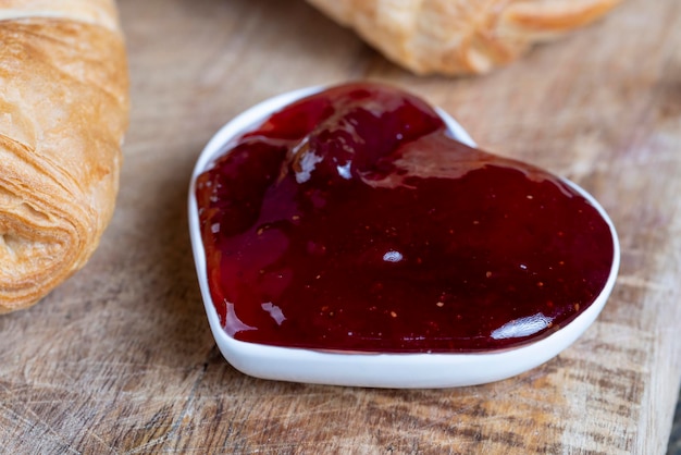 Bladerdeeg met rode aardbeienjam op een houten tafel