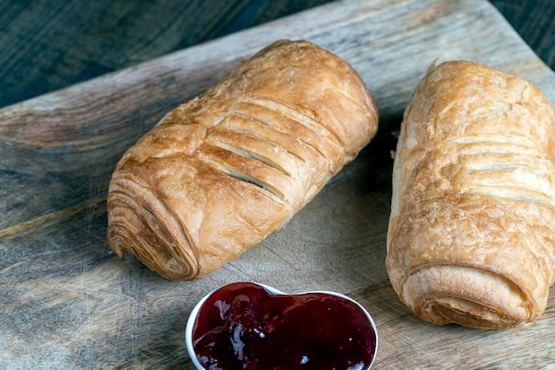 Bladerdeeg met rode aardbeienjam op een houten tafel