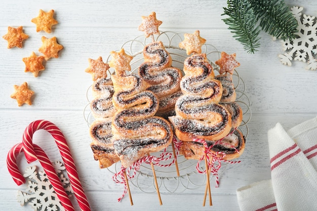 Bladerdeegcakes in de vorm van een kerstboom met chocoladevulling, suikerpoeder en lolly's op oude witte houten achtergrond Kerstmis Nieuwjaar Voorgerecht Feestelijk idee voor Kerstmis of Nieuwjaarsdiner