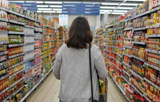 Bladeren door de gangpaden Achteraanzicht van een vrouw die door een gangpad in een supermarkt bladert