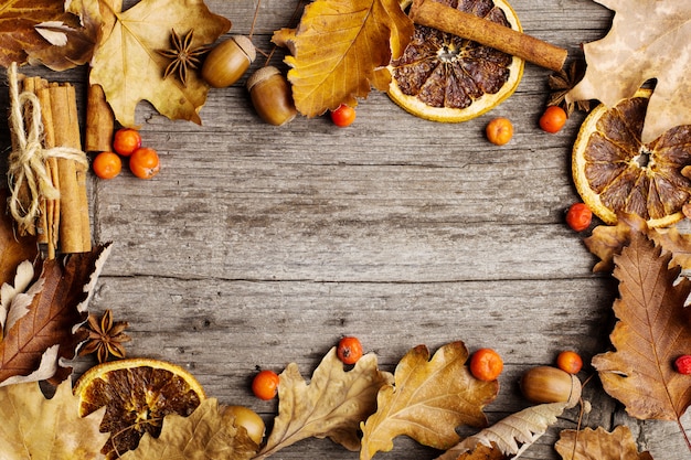 Foto bladeren, droge sinaasappel, kaneel en eikels op de oude houten tafel, kopie ruimte, herfst.