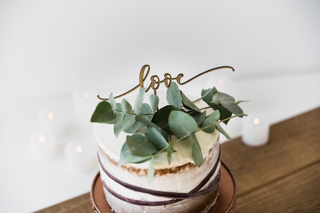 Bladeren en liefdetekst op decoratieve ronde cake over de houten lijst