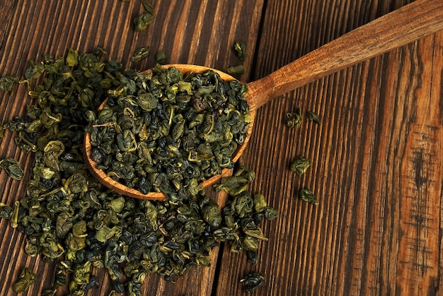 Bladeren van groene thee in een houten lepel op vintage tafel