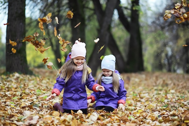 Bladval in het park. Kinderen voor een wandeling in het herfstpark. Familie. Val. Blijheid.