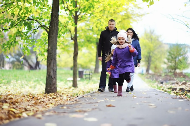 Bladval in het park. Kinderen voor een wandeling in het herfstpark. Familie. Val. Blijheid.