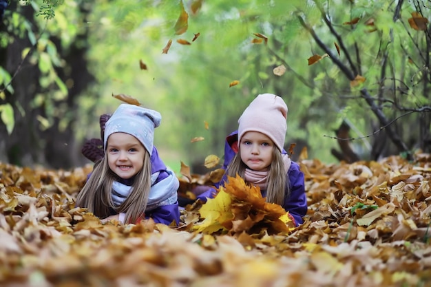 Bladval in het park. Kinderen voor een wandeling in het herfstpark. Familie. Val. Blijheid.