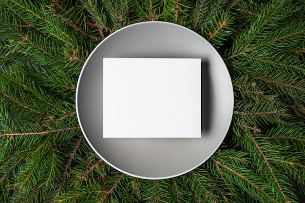 Blanc card on gray plate, full frame of fir branches background. Letter with congratulations, letter to Santa Claus. High quality photo