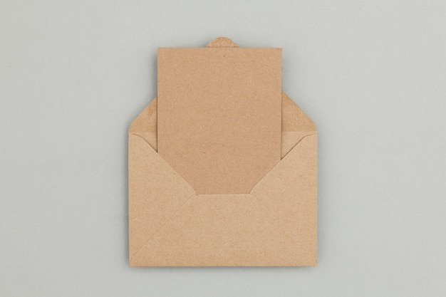Foto blanco bruine kraftpapier kaart en envelop op een grijze achtergrond