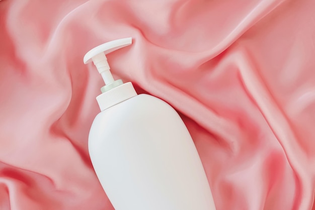 Blanco cosmetische containerfles als productmodel op roze zijden achtergrond