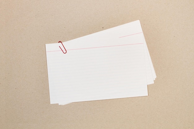 Blanco gestreepte papieren notities met een paperclip op een bruine achtergrond met kopieerruimte