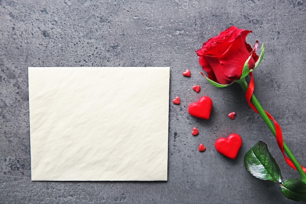 Blanco huidige valentijnskaart met mooie roos op grijze gestructureerde achtergrond