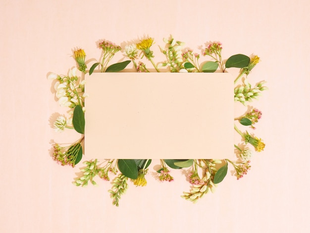Blanco papier met frame van bloemen. Plat leggen, ruimte kopiëren, bovenaanzicht.