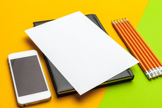 Blanco papier met smartphone en potloden