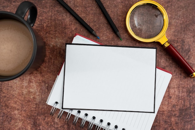 Blanco papier met spiraal notebook potloden koffiemok en vergrootglas liggend houten oppervlak het vertegenwoordigt analyseren en brainstormen nieuwe zakelijke ideeën