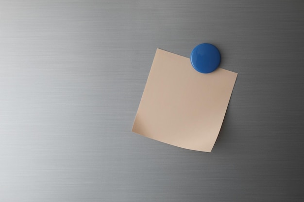 Blanco papier op koelkastdeur met blauwe magneet