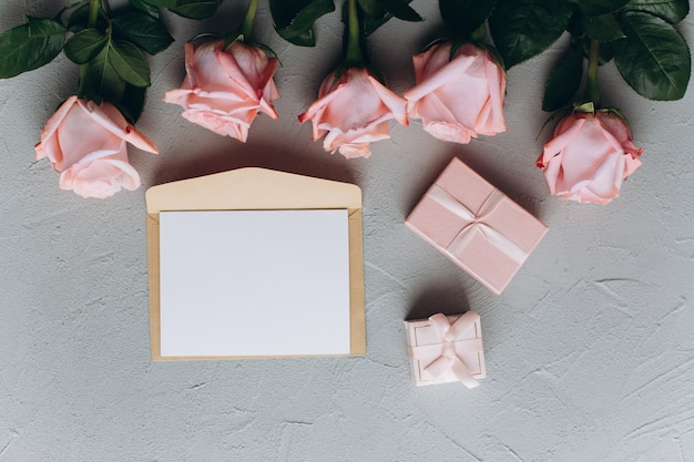 Blanco papier opmerking met envelop, geschenken en roze roos