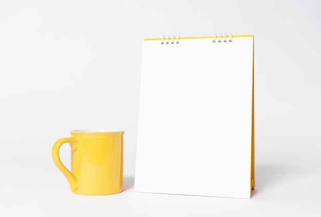 Blanco papier spiraal kalender en gele beker voor mockup sjabloon