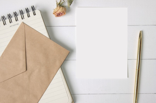 Blanco papieren kaart ambachtelijke envelop spiraal notebook gouden pen en een roos