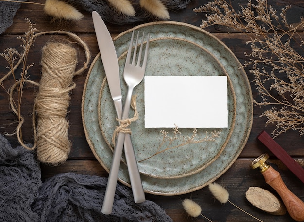 Blanco papieren kaart op bord met vork en mes op houten tafel met Boheemse decoratie