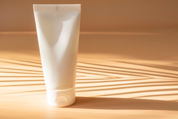 Blanco plastic buismodel voor cosmetica met dop op beige achtergrond met zonneschaduw Zomer trendy adv-ontwerp voor huidverzorgingscosmetica