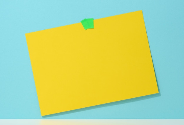 Blanco rechthoekig geel vel papier gelijmd op een blauwe achtergrond. Plaats voor een inscriptie, aankondiging