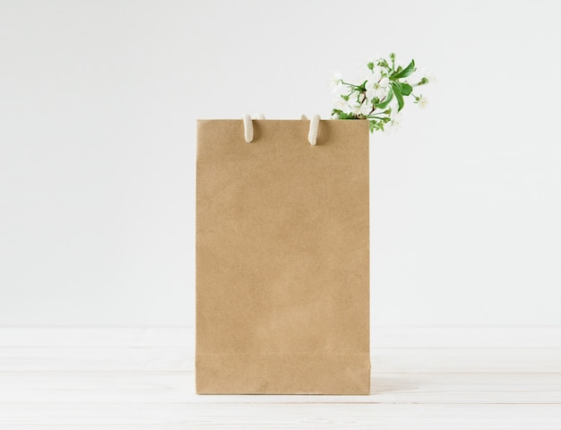 Foto blanco van bruine ambachtelijke papieren zak met handvatten. witte achtergrond. verse bloemen.