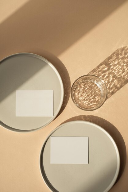 Blanco vel papier kaart met mockup kopie ruimte Minimale luxe esthetische zakelijke merksjabloon Glas met zonlicht schaduwen keramische platen op neutrale peachy achtergrond Plat lag bovenaanzicht