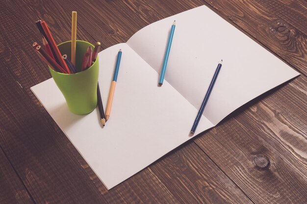 Blanco vel papier met een glas met potloden en potloden zijn ook op een papier op de houten tafel