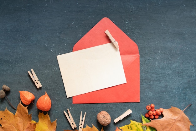 Blanco vel papier Plat lag oranje herfstbladeren en envelop, physalis op een donkere achtergrond