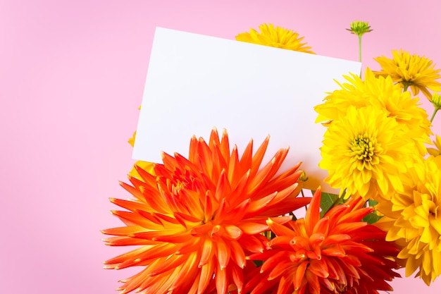 Blanco wenskaart in een boeket van gele en rode zomerbloemen op een roze achtergrond