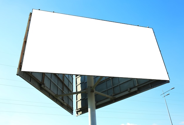 Blank advertising board outdoors against blue sky