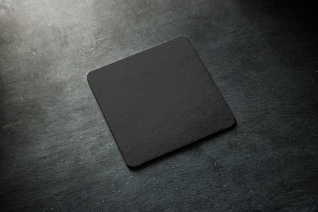 Blank black beer coaster  lying on grey desk