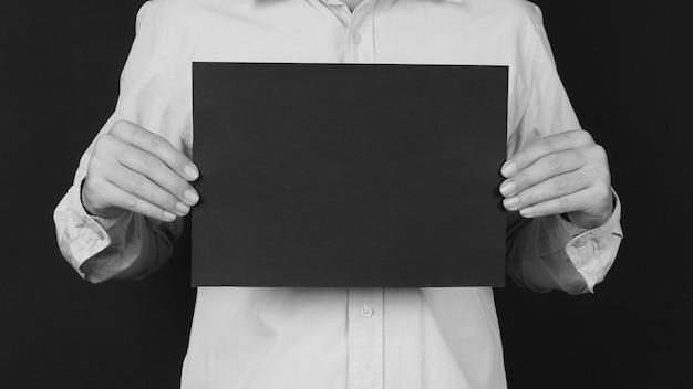 Blank black board A4 paper in man hand covered face and wear blue shirt on black backgroundx9