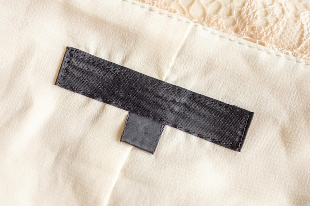 Blank black laundry care clothing label on fabric texture