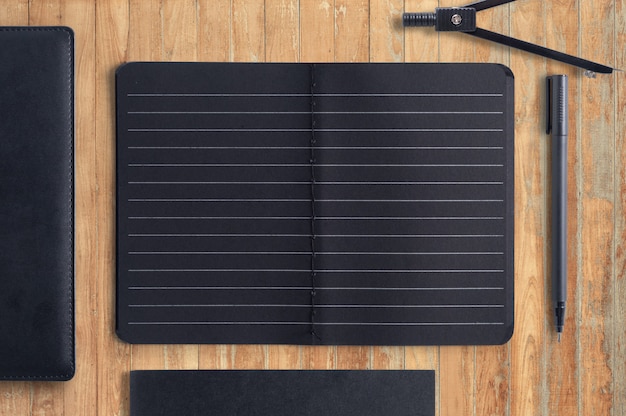 Blank black notebook and pen on wood background