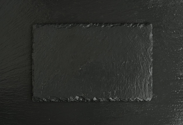 Blank black stone slate plate on black slate background top
view with copy space