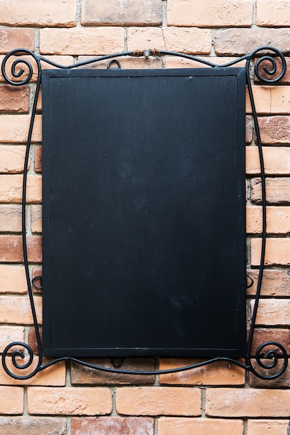 Photo blank blackboard at a brick wall - nice background with space for text