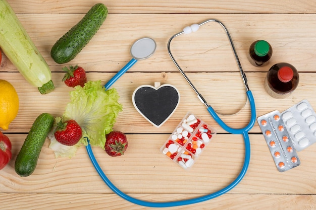 Blank blackboard in shape of heart stethoscope and choice between natural vitamins vegetables