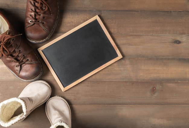 Blank blackboard with father and son brown leather boots shoes 