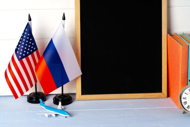 Photo blank blackboard with usa and russia flags on wooden background