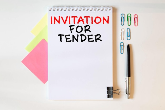 Blank blad pen en gerimpelde papieren ballen op een grijze tafel plat gelegd Text INVITATION FOR TENDER