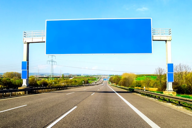 Blank blue freeway sign over the road on sunny day