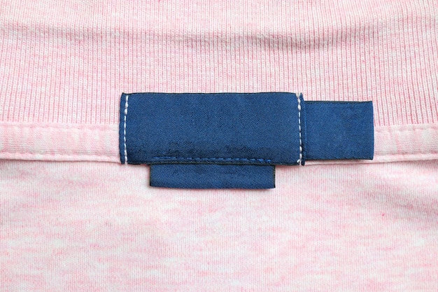 Photo blank blue laundry care clothes label on pink shirt fabric texture background