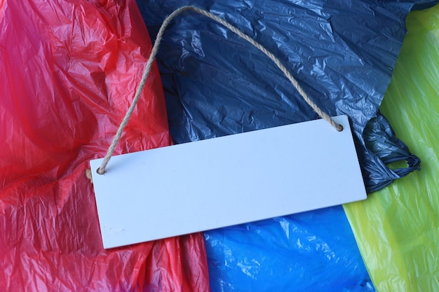 Фото Пустая доска для текста на пластиковых пакетах разных цветов в качестве фона.