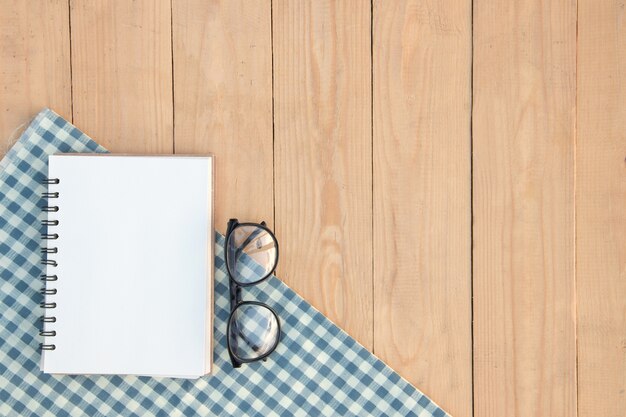 Blank book and eyeglasses on white and blue plaid 