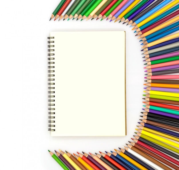 Blank book surrounded by pencils of various colors